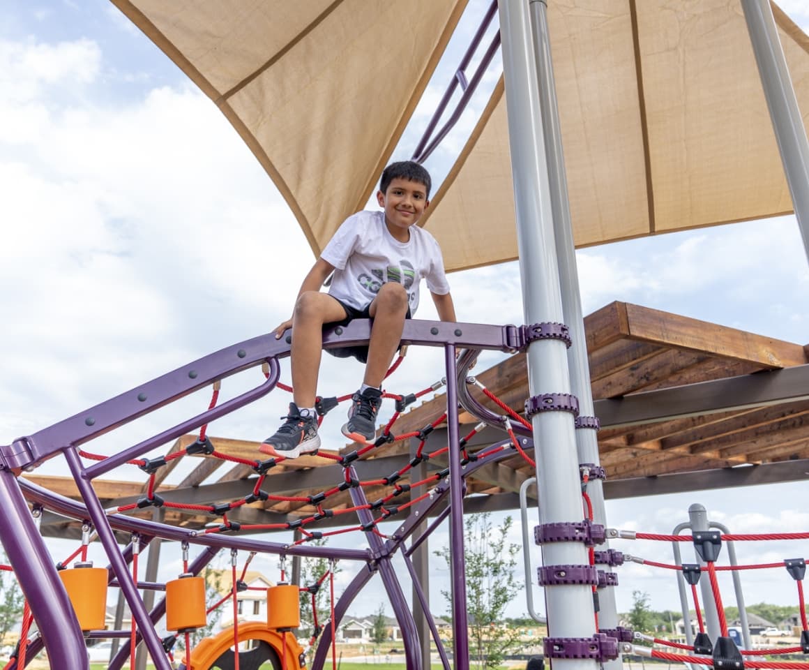 A boy on a climbing structure in a playground.