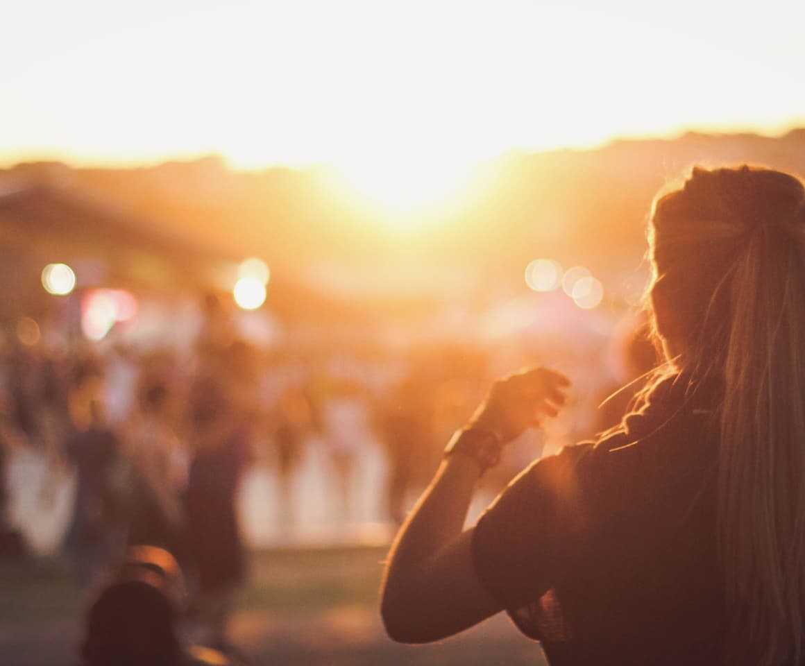 A woman looking at the sun at an outdoor concert.