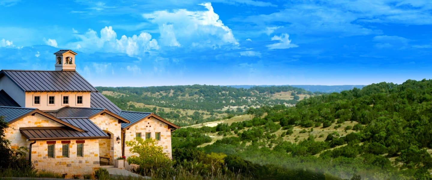 A house on a hill in the middle of a forest.