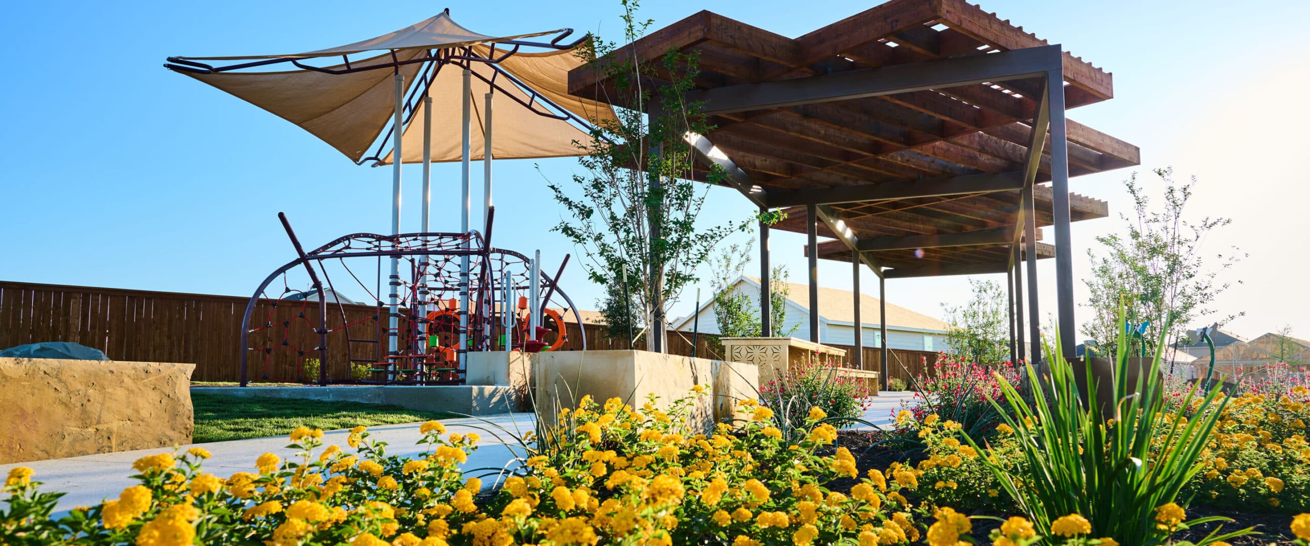 A playground with a wooden structure and yellow flowers.