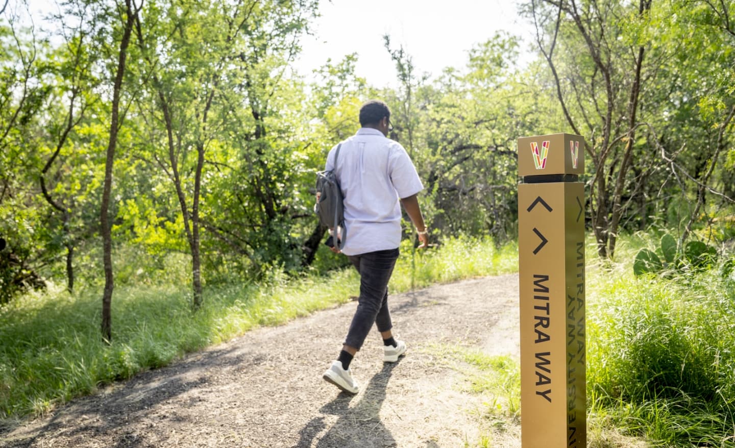 A man walking down a trail in the woods.