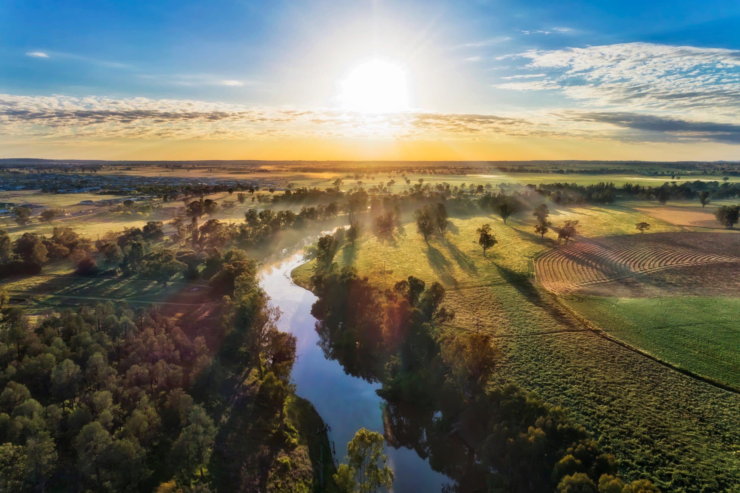 An aerial view of a rural landscape with a river in the background.