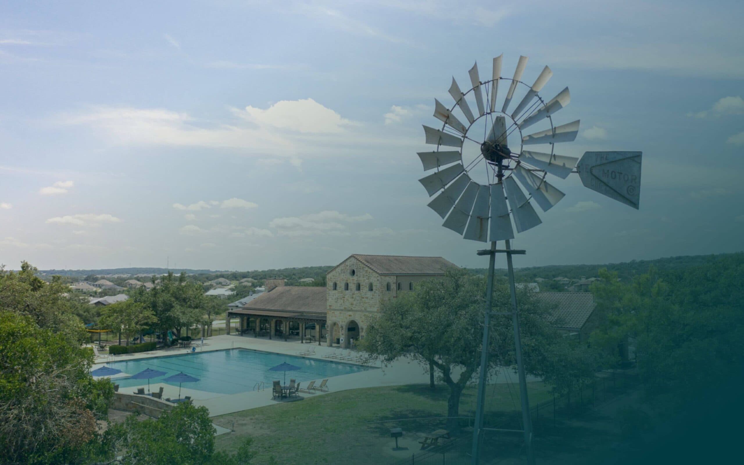 A windmill in front of a swimming pool.