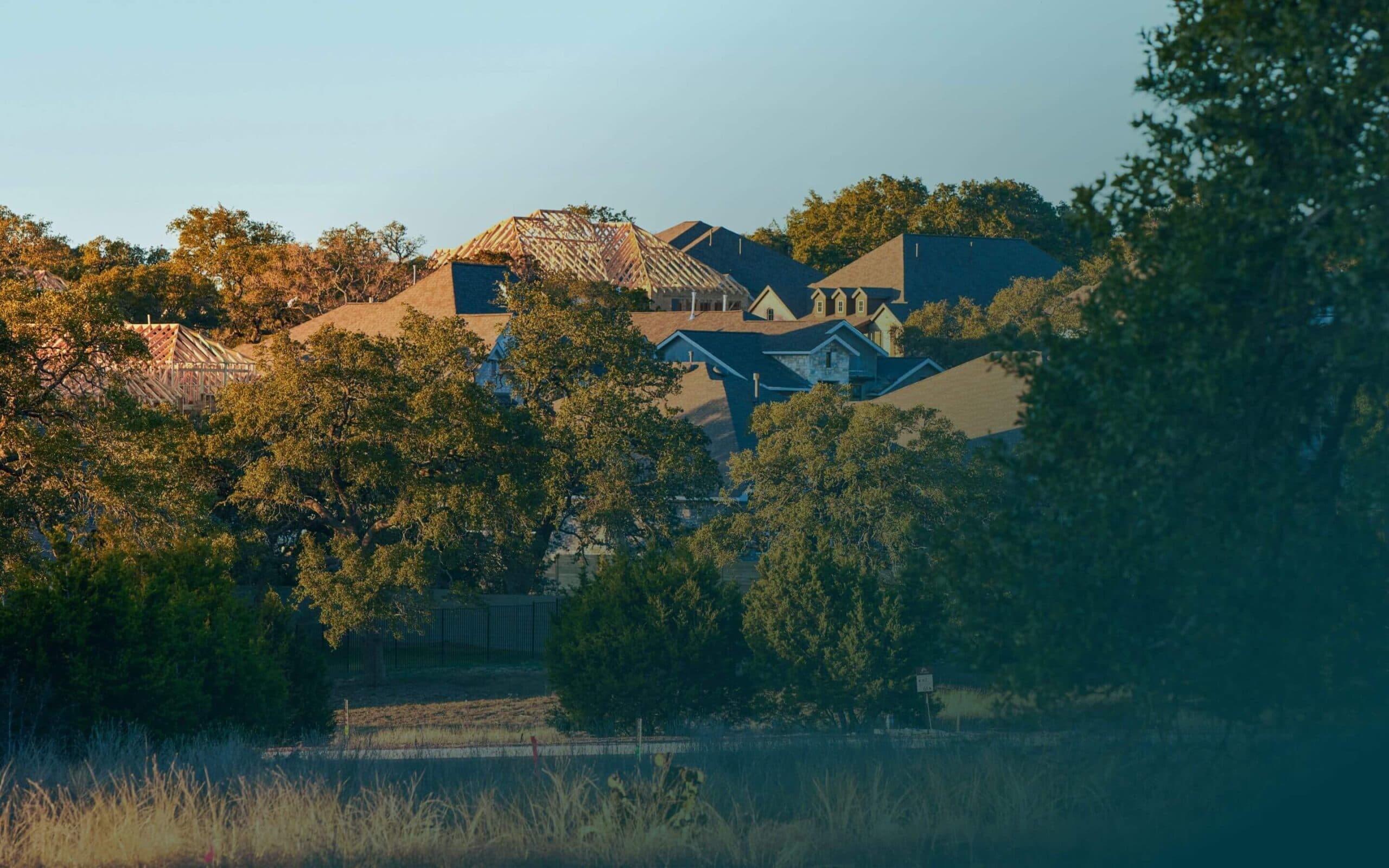 A group of houses with a trees and grass in front of them