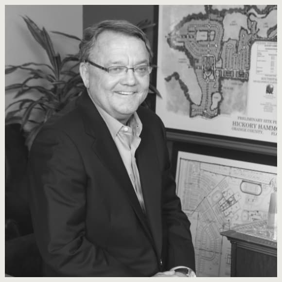 A black and white photo of Larry Rutherford sitting in front of a map.