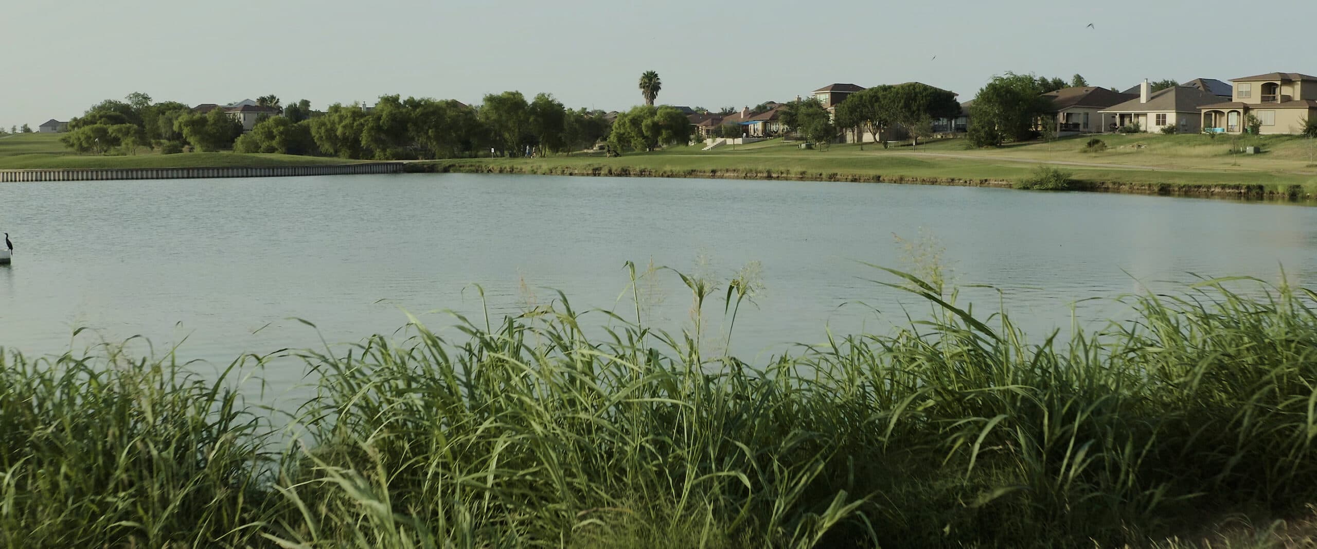 A golf course with a pond in the background at Mission del Lago
