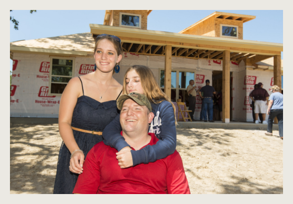 A family posing for a picture in front of their new home.