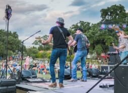 A group of musicians on stage at an outdoor concert.