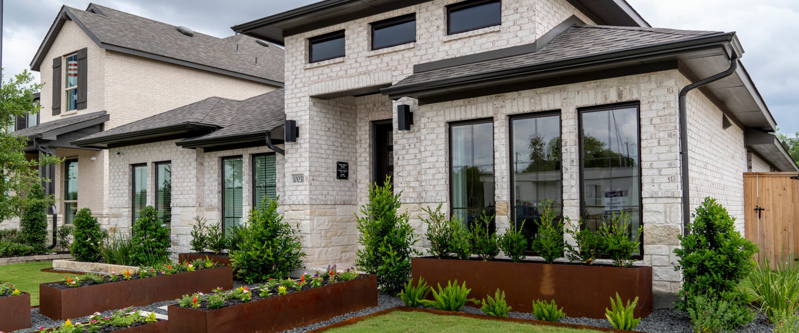A home with many windows and a large front yard with planters.